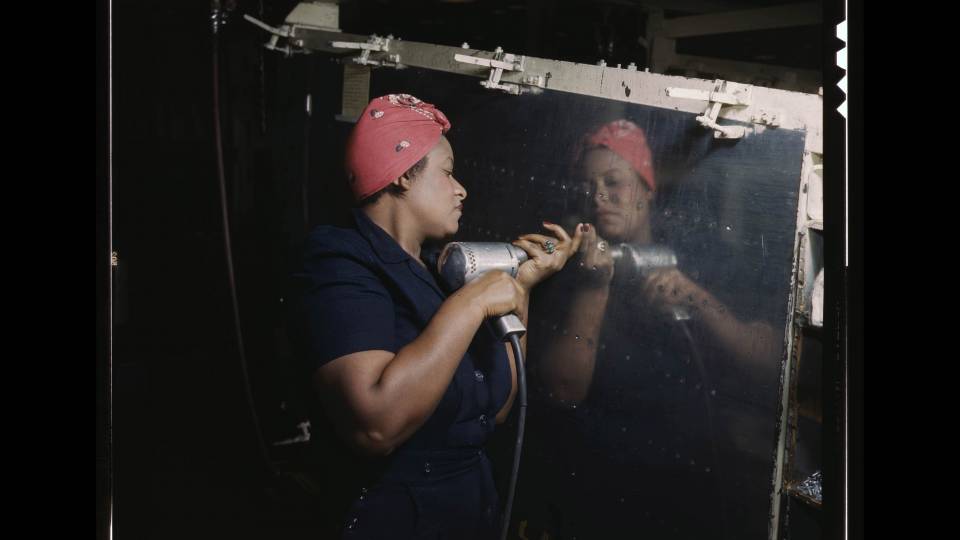 A woman installs rivets in the wartime labor effort