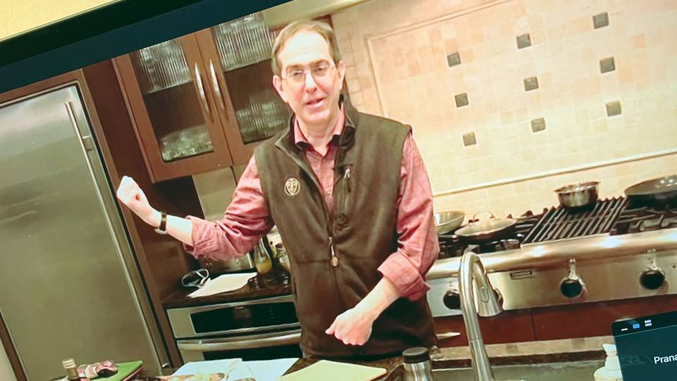 Christoper Eisgruber shown in a video, holding up an egg in a kitchen