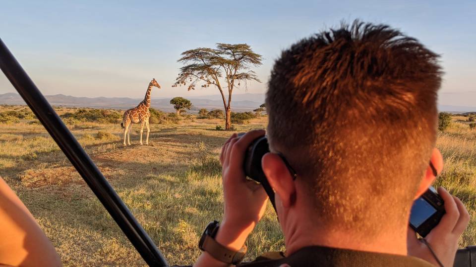 Luca Kuziel looks at a giraffe through a camera lens