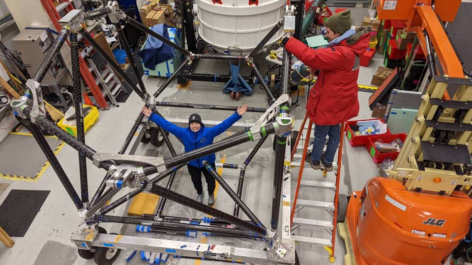 Susan Redmond raising her arms amid equipment in a laboratory in Antarctica.