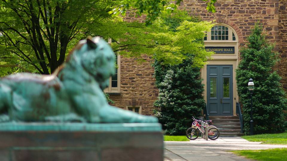 A bronze tiger sculpture in the foreground with Princeton's Stanhope Hall