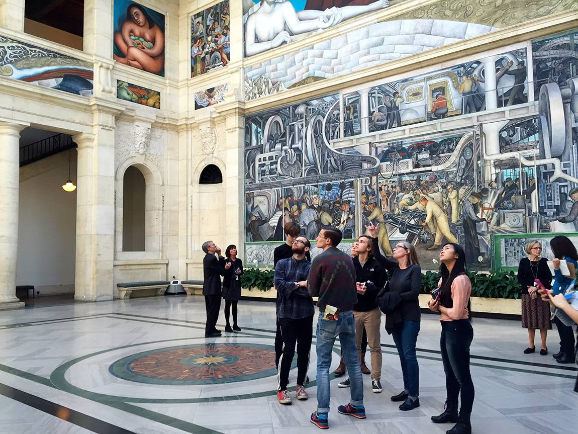 Professor Judith Hamera explains part of Diego Rivera's Detroit Industry fresco cycle to students during a visit to the Detroit Institute of Arts.