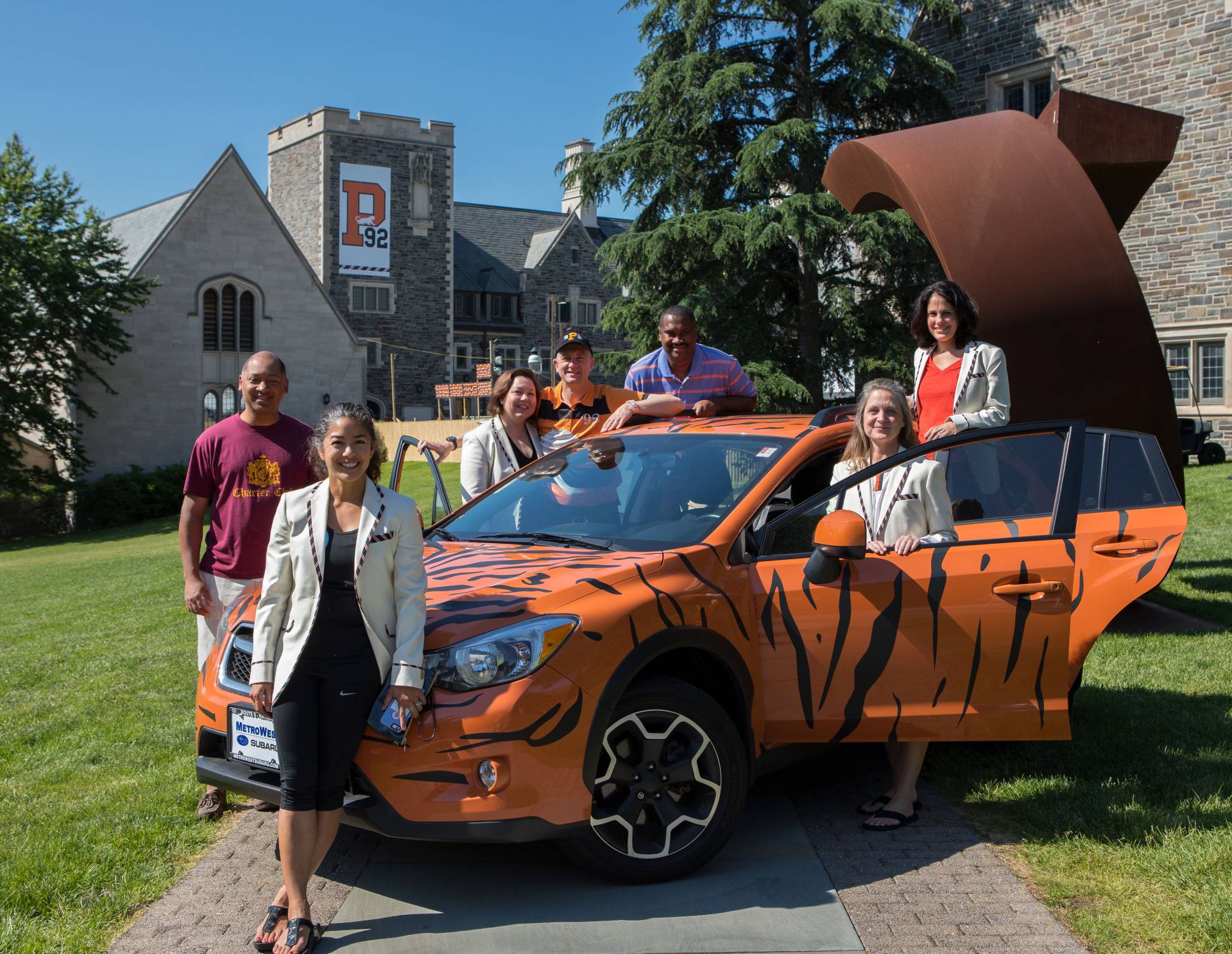 Alumni from class of 1992 pose around tiger striped car