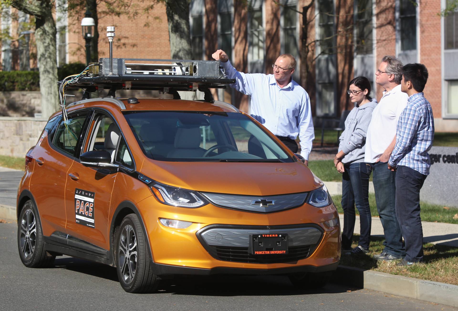 Researchers stand next to electric car