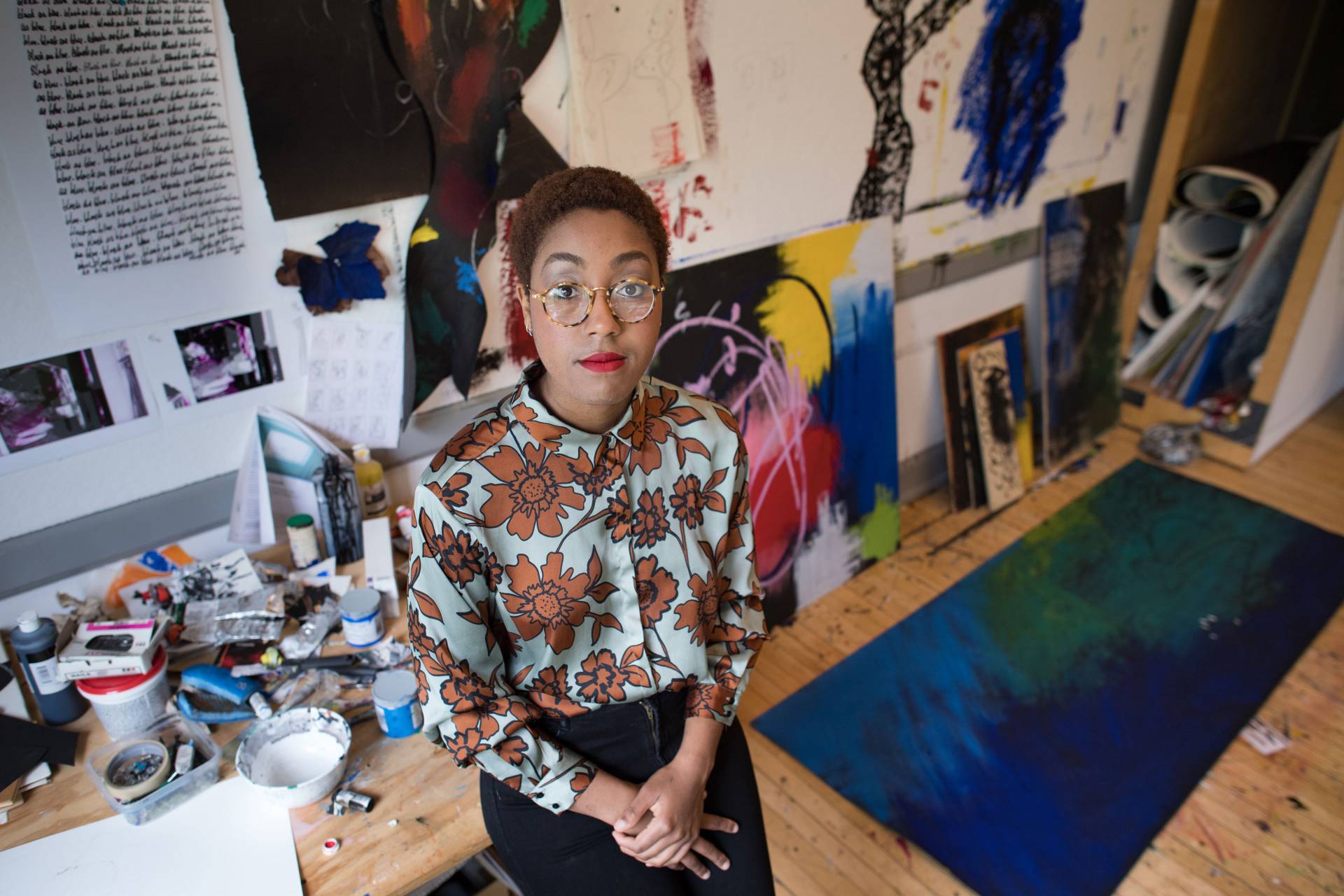 Imani Ford in front of her paintings and artwork
