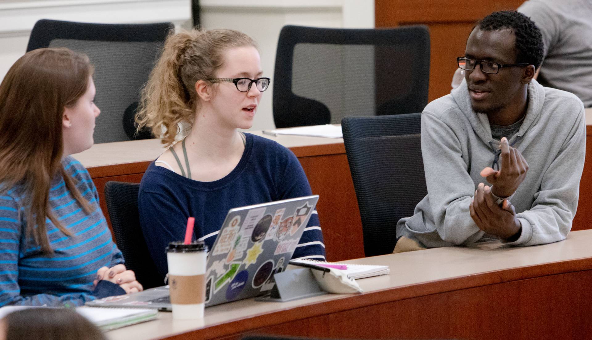 Madeline Pollack, Amanda Koym and Peter Mwesigwa talking to each other during class