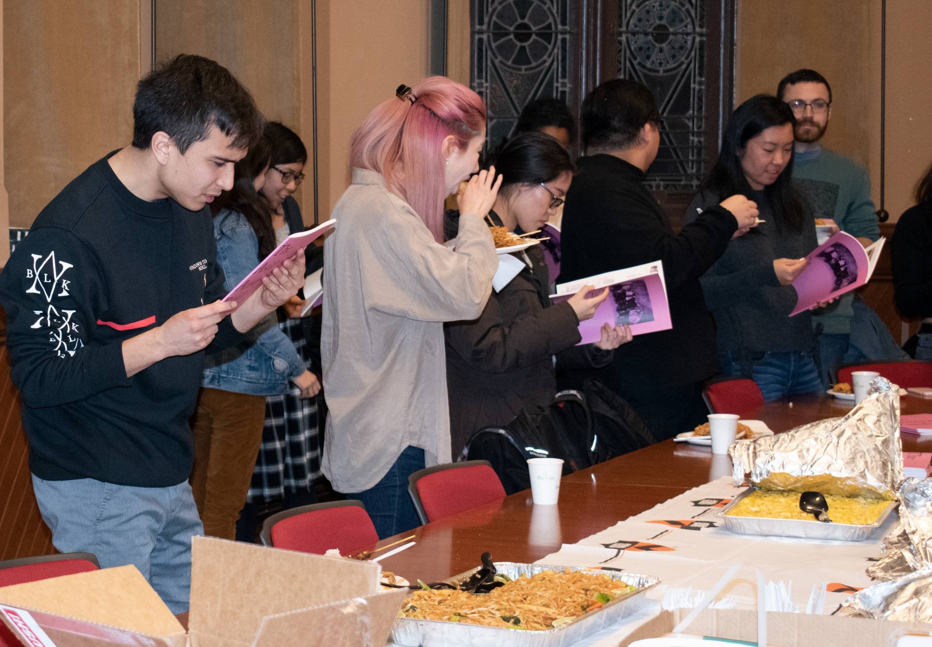 Sudents gather around looking at the bound copies of the Asian American Family zine at the launch party