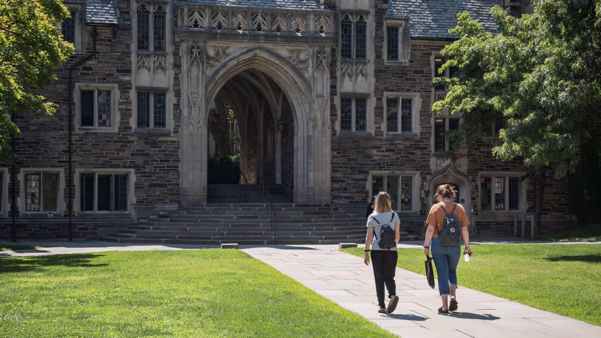 Two students walking toward an arch on campus