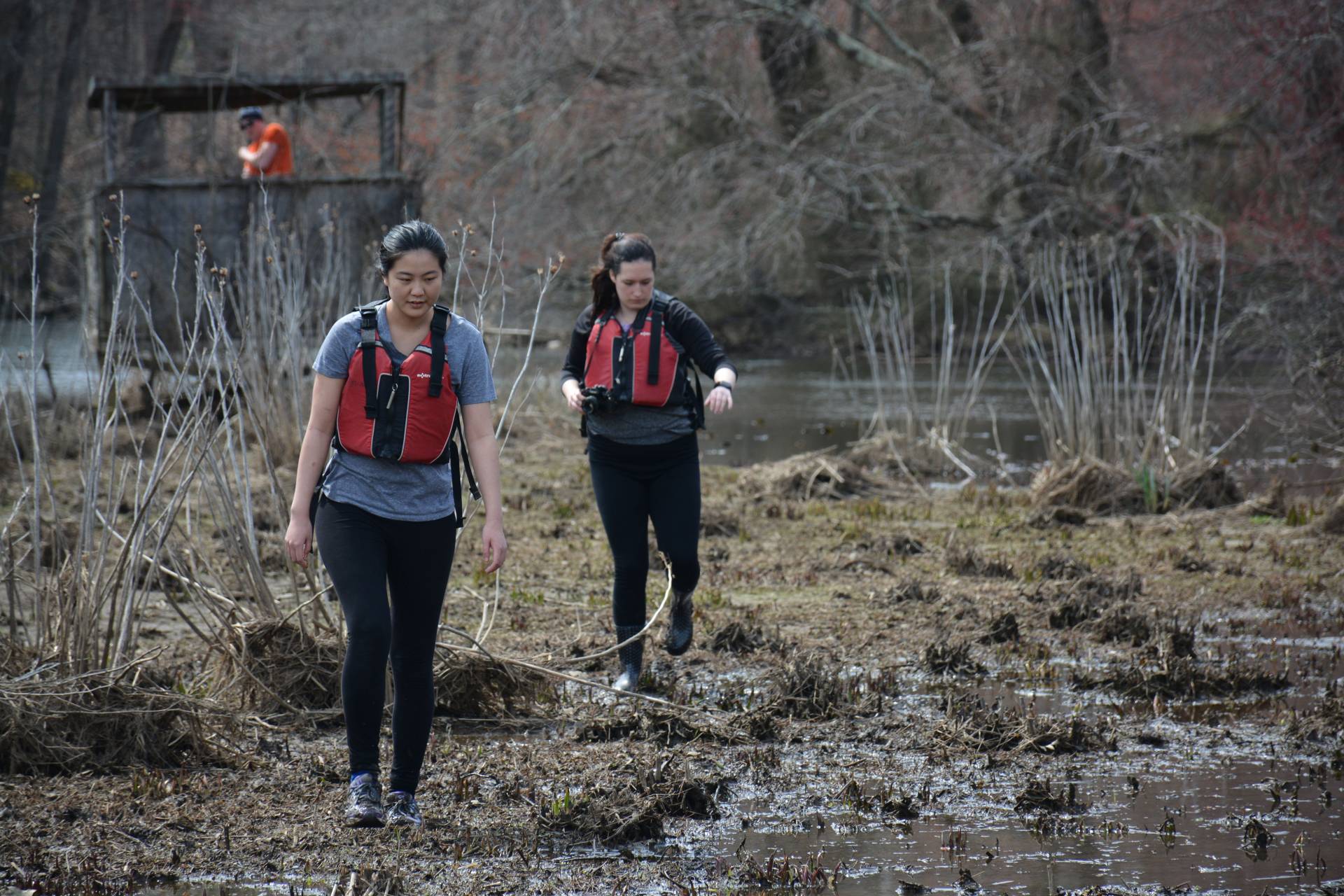 Two students walk along the banks of the river