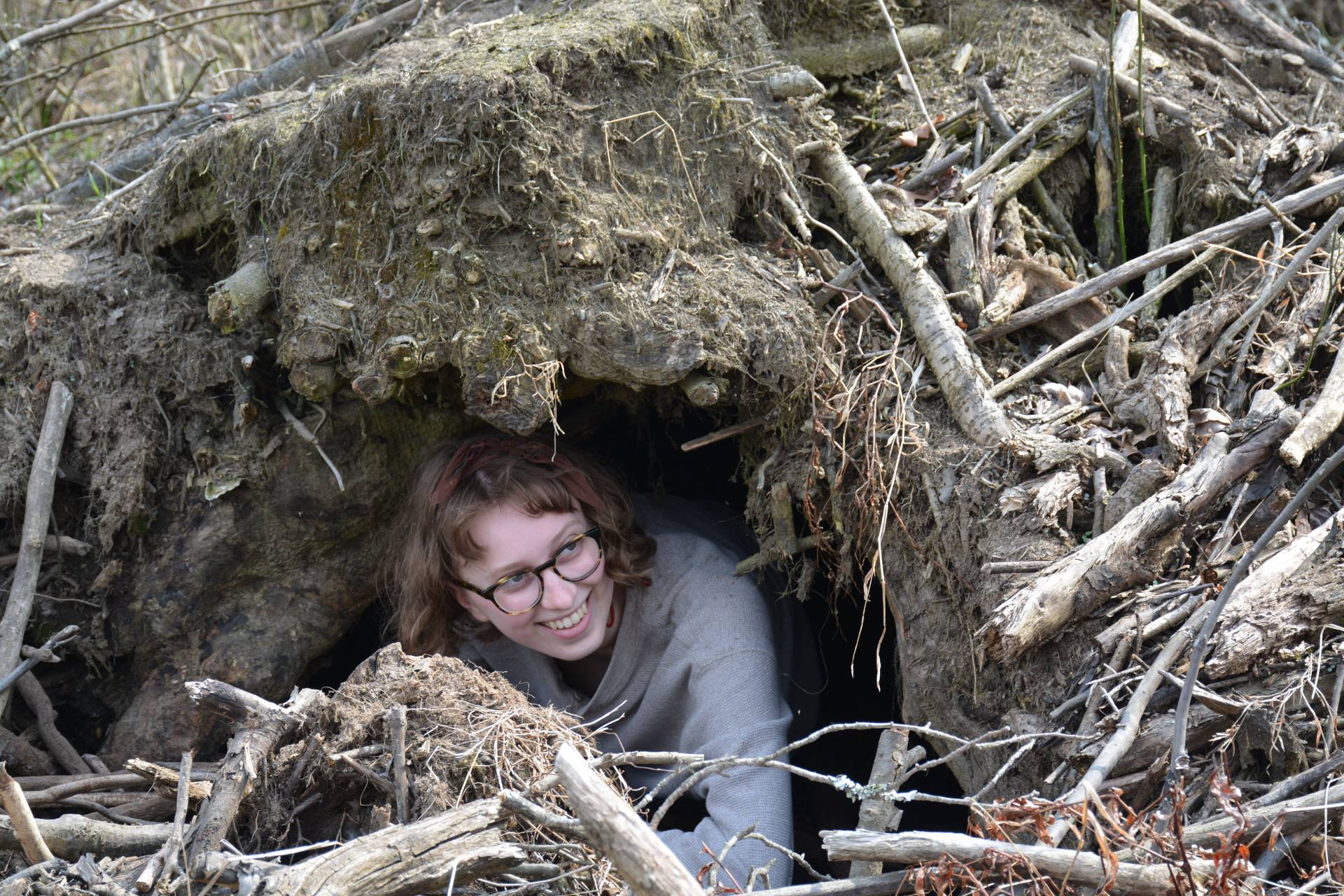 A student peeks out from an abandoned beaver lodge