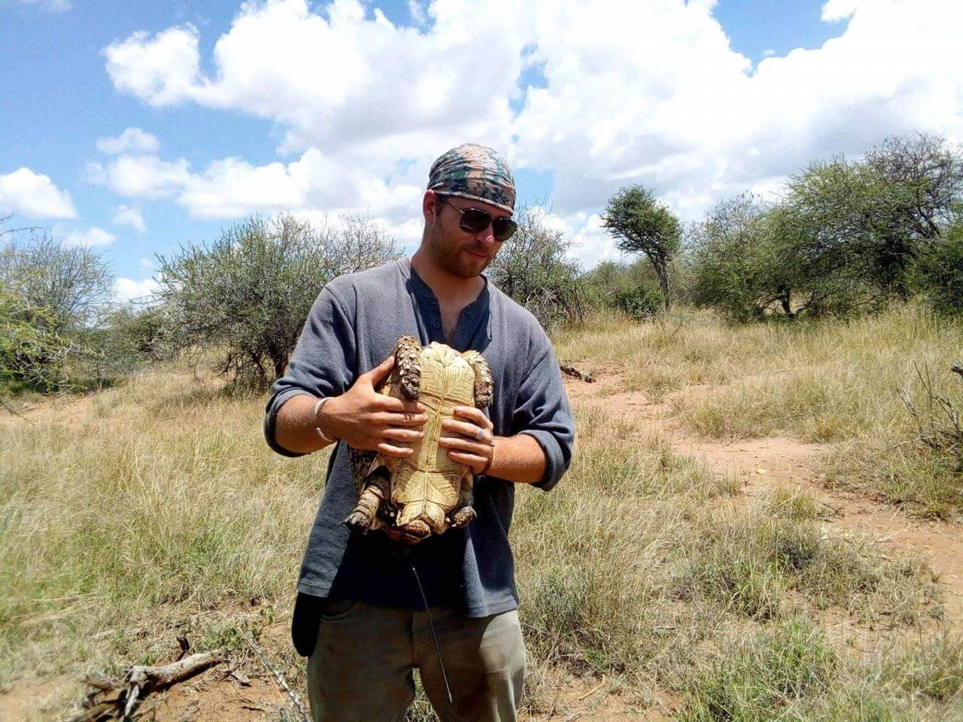 Daniel Petticord outside holding a tortoise