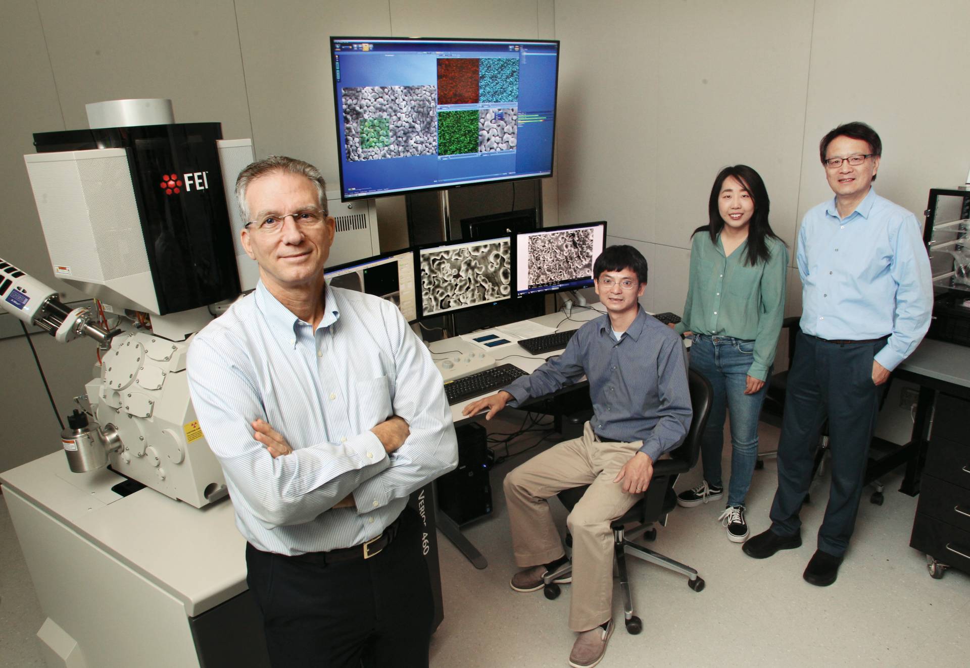 Researchers sit and stand infront of a large display