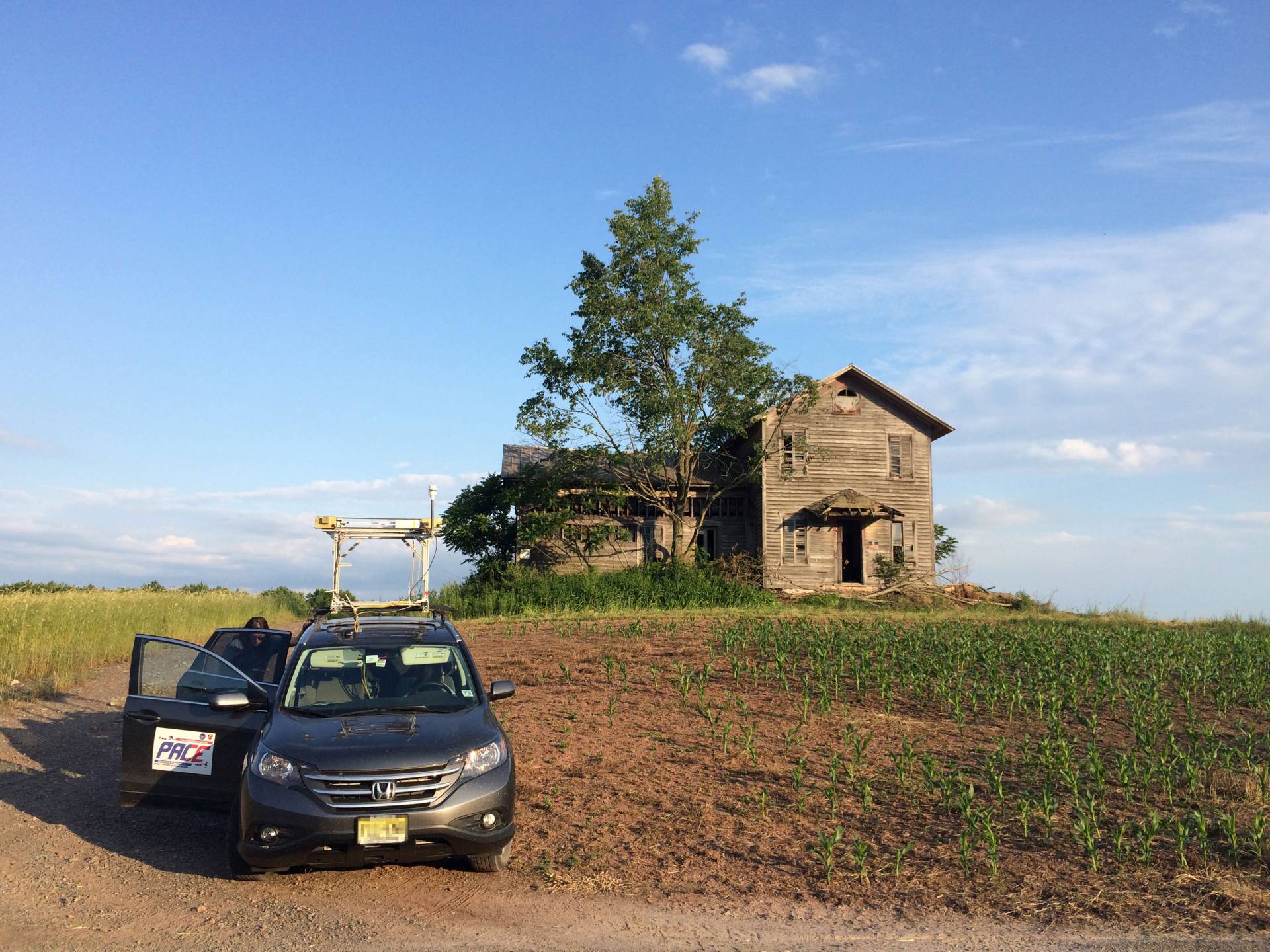 Mobile lab in front of farmhouse in a corn field