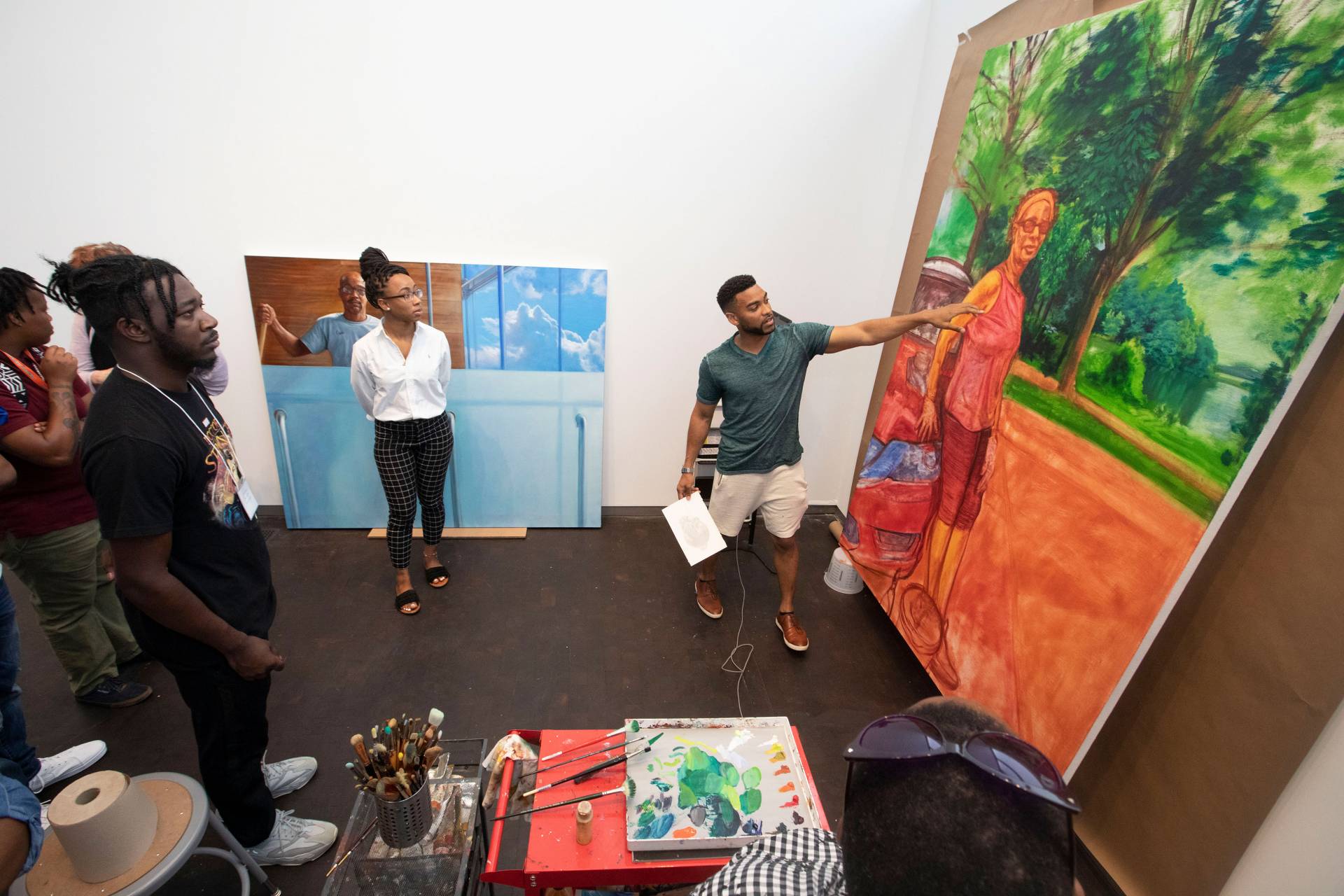 Painter Mario Moore points at a large unfinished painting on a tour of his studio