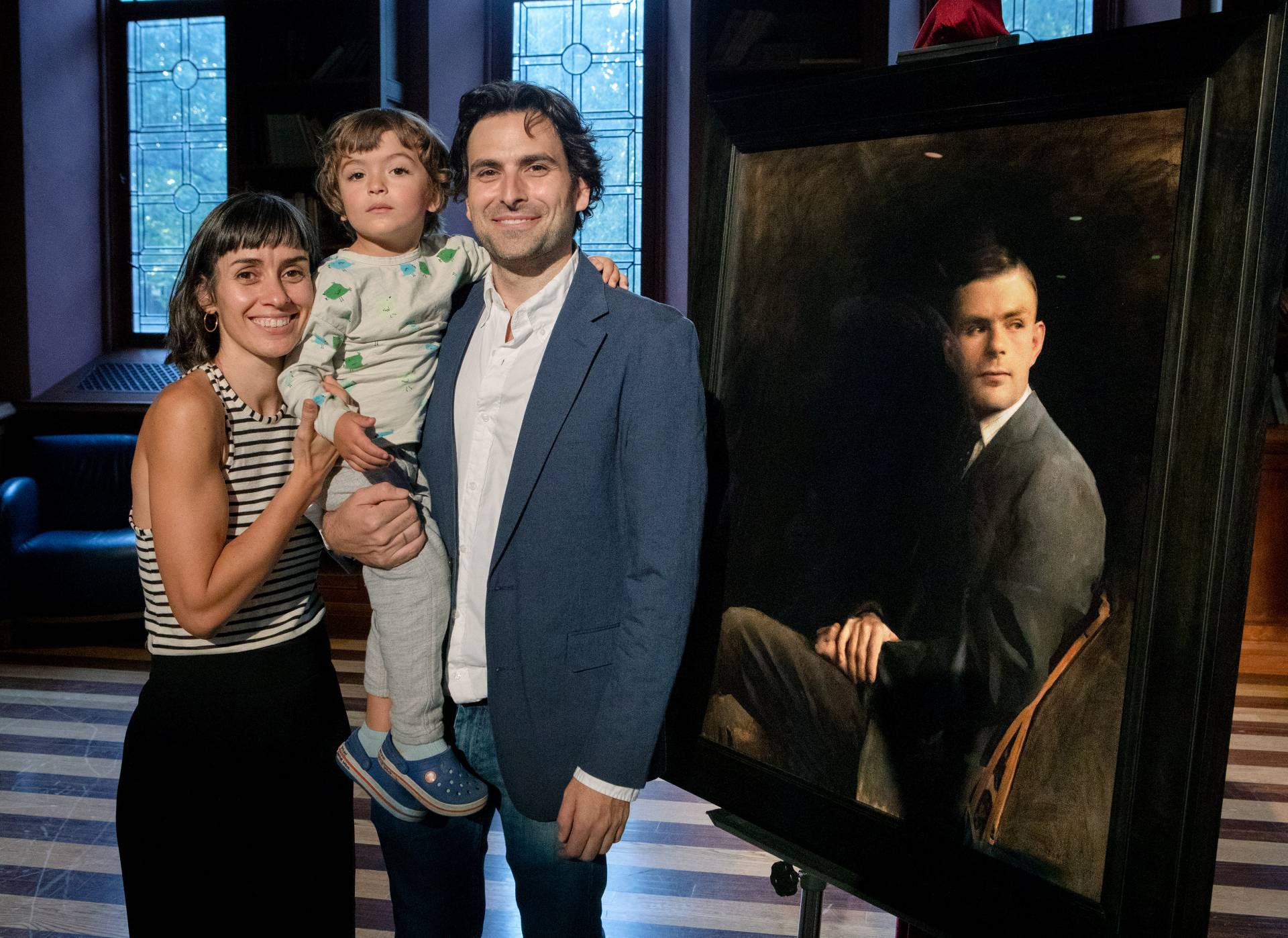 The artist and his family pose next to the portrait of Alan Turing