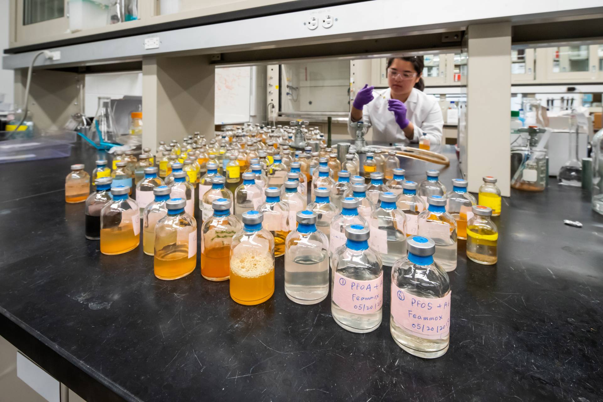 A researcher looks at many bottles of liquid samples