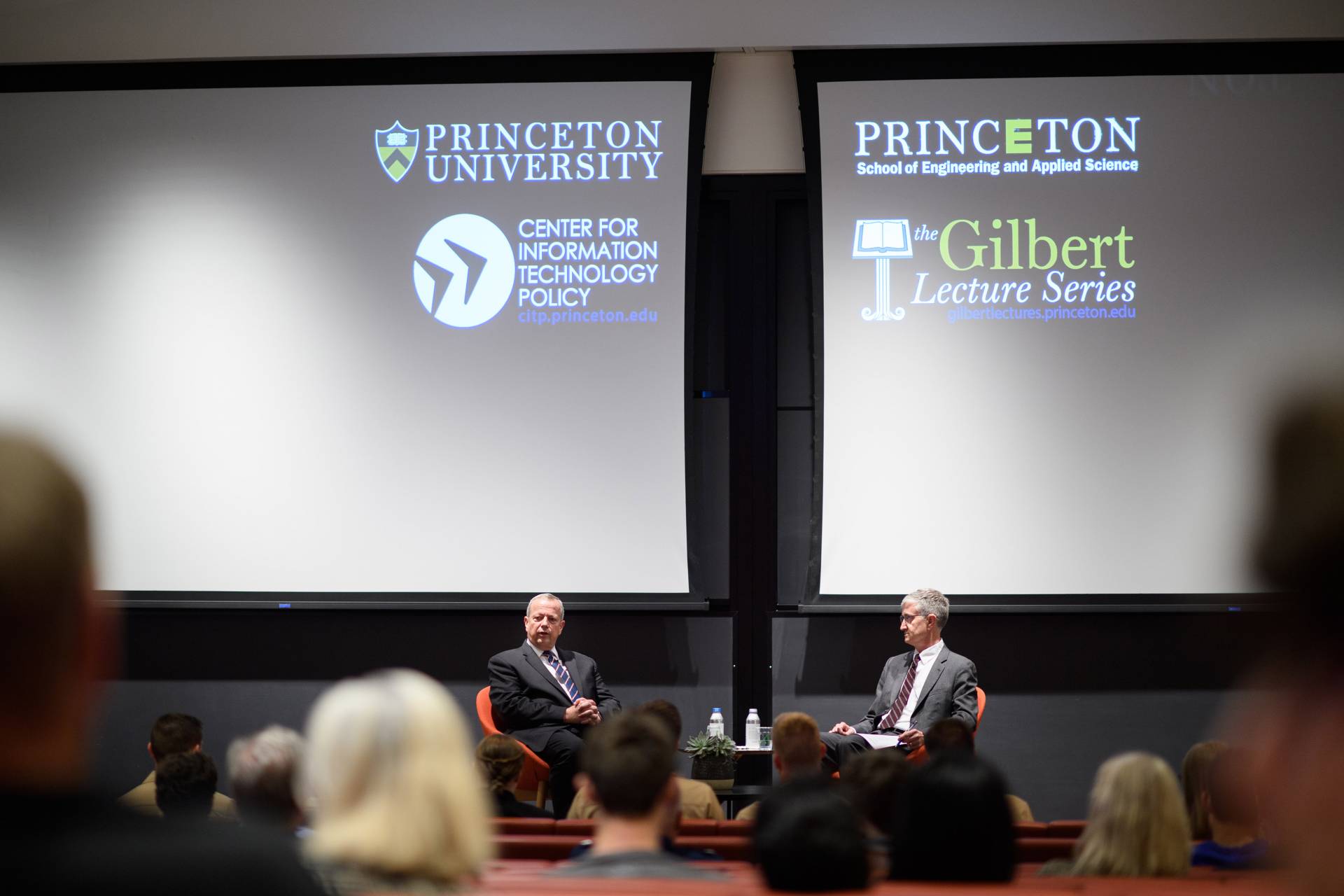 2 men on a stage with projections of Princeton University School of Engineering and Applied Science, CITP, Princeton University, and the Gilbert Lecture Series logos on a screen 