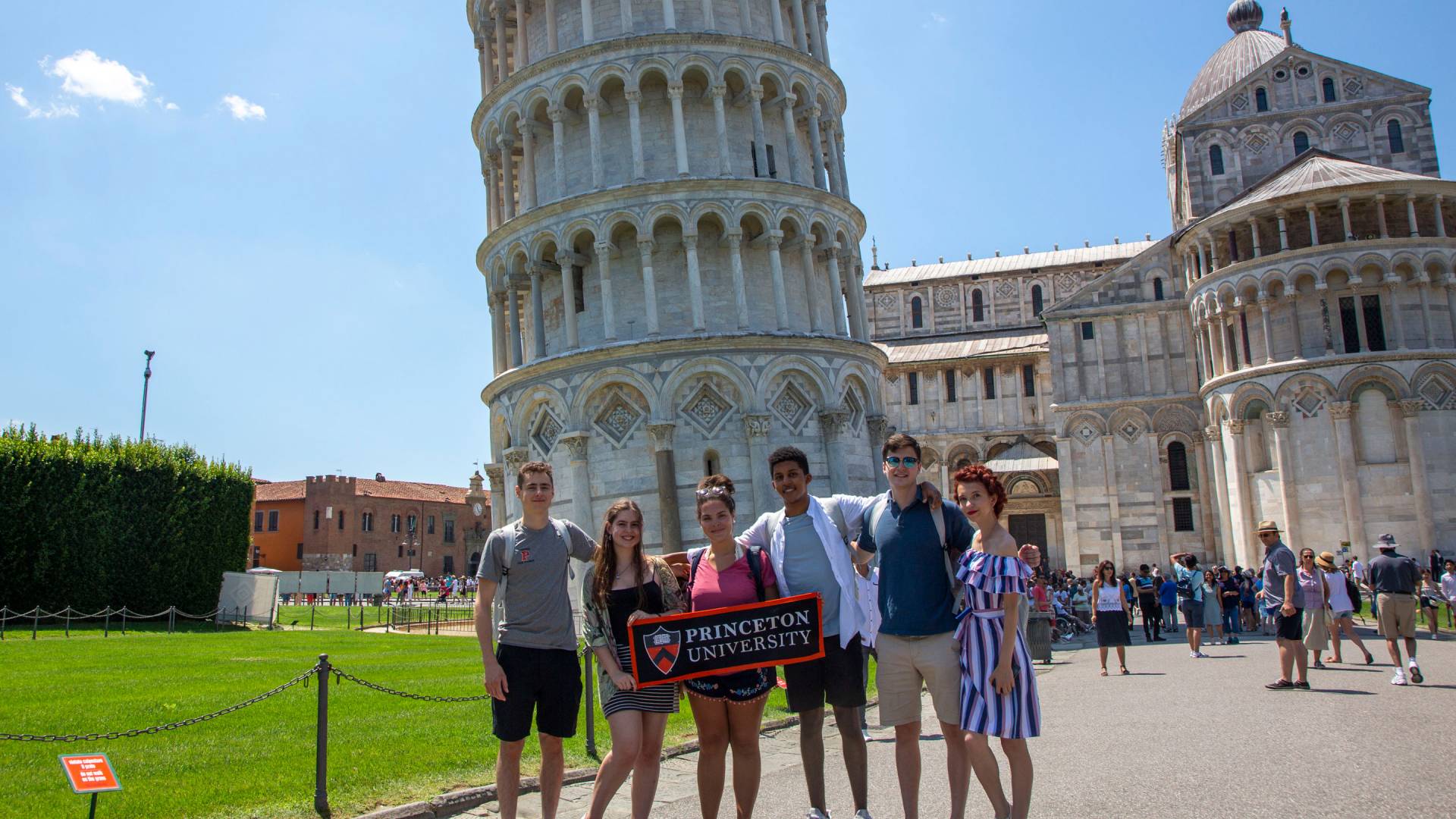 Students standing holding Princeton banner in front of tower of Pisa