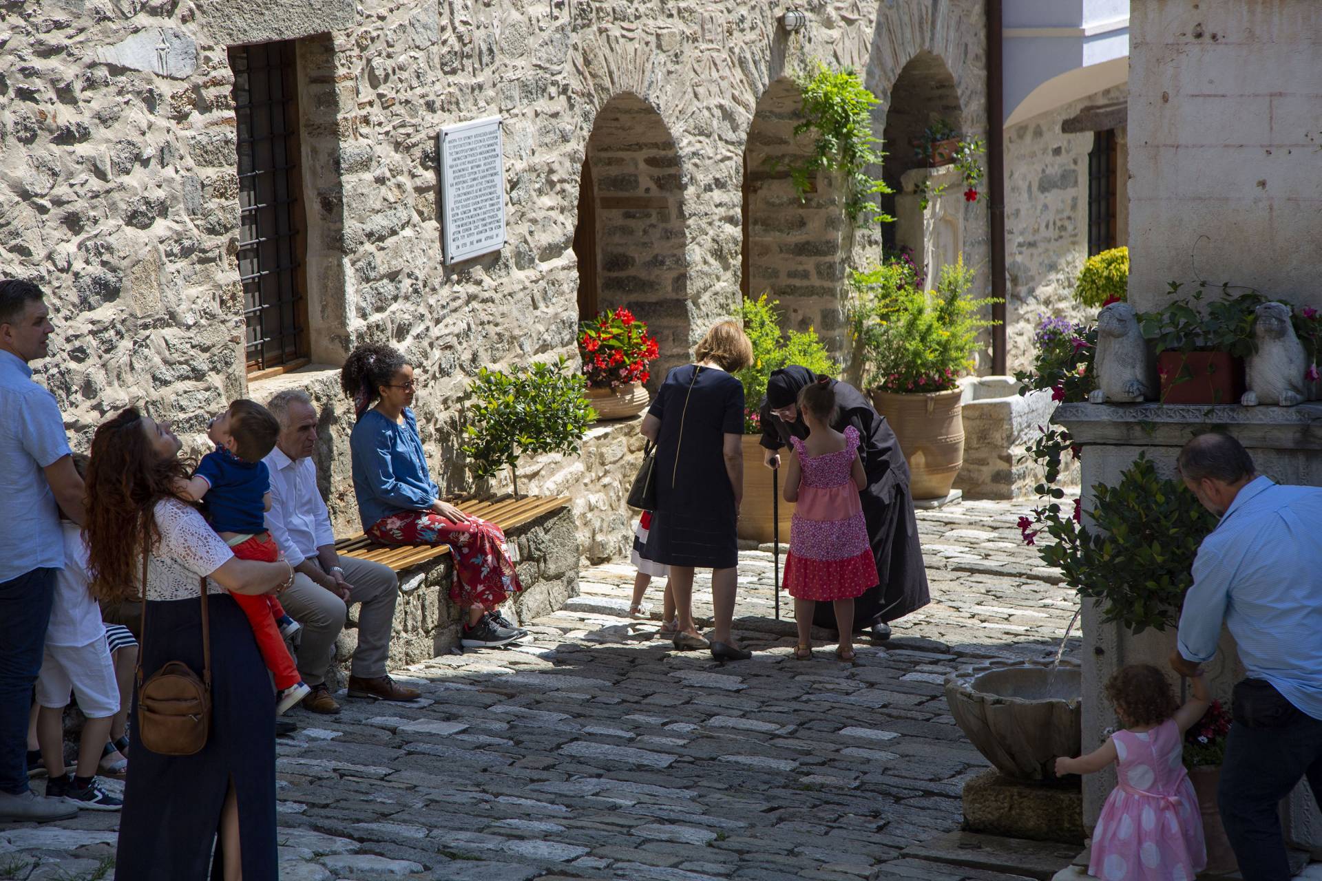 A nun bows her head in conversation with a family