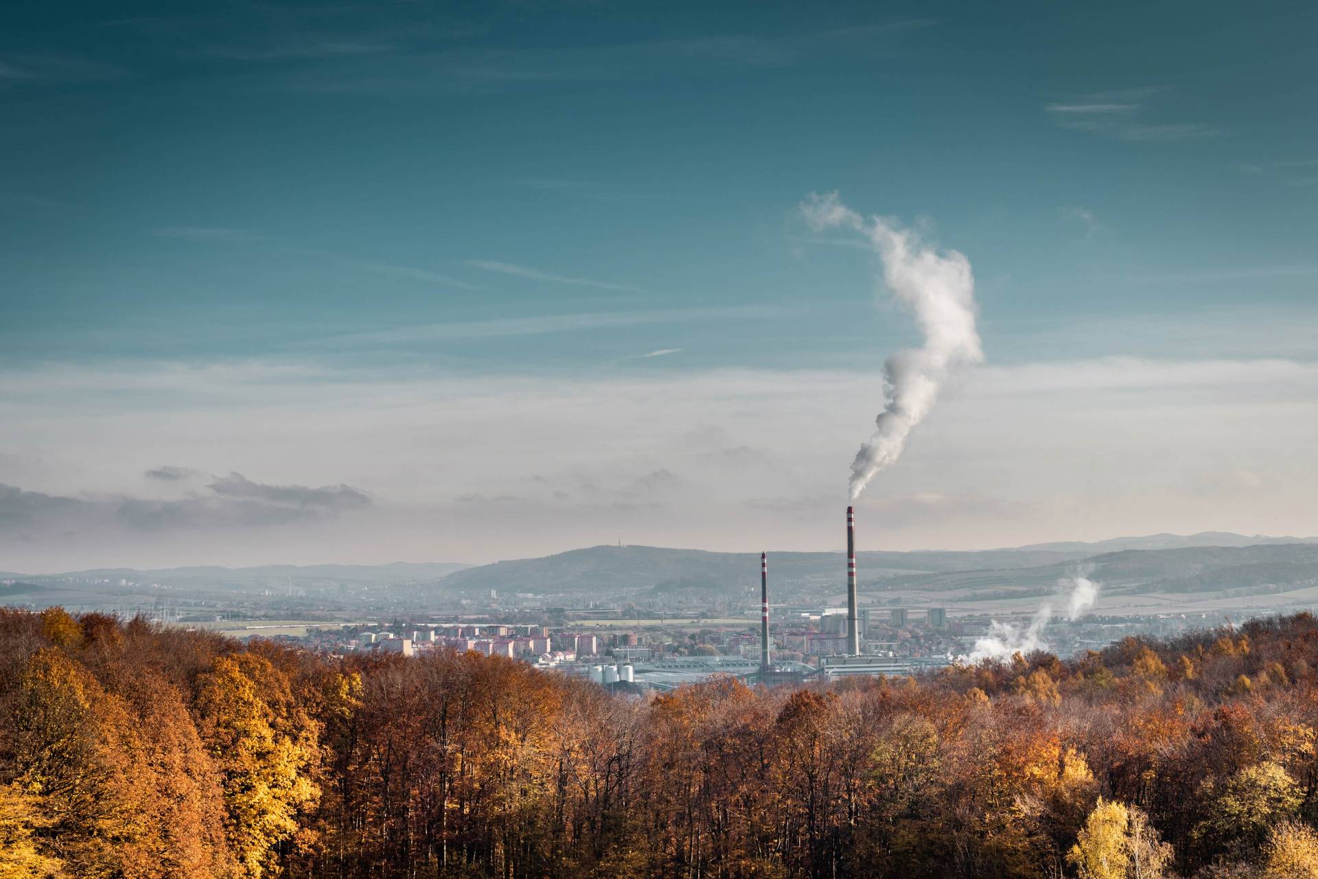 landscape of autumn trees and smokestacks in the background