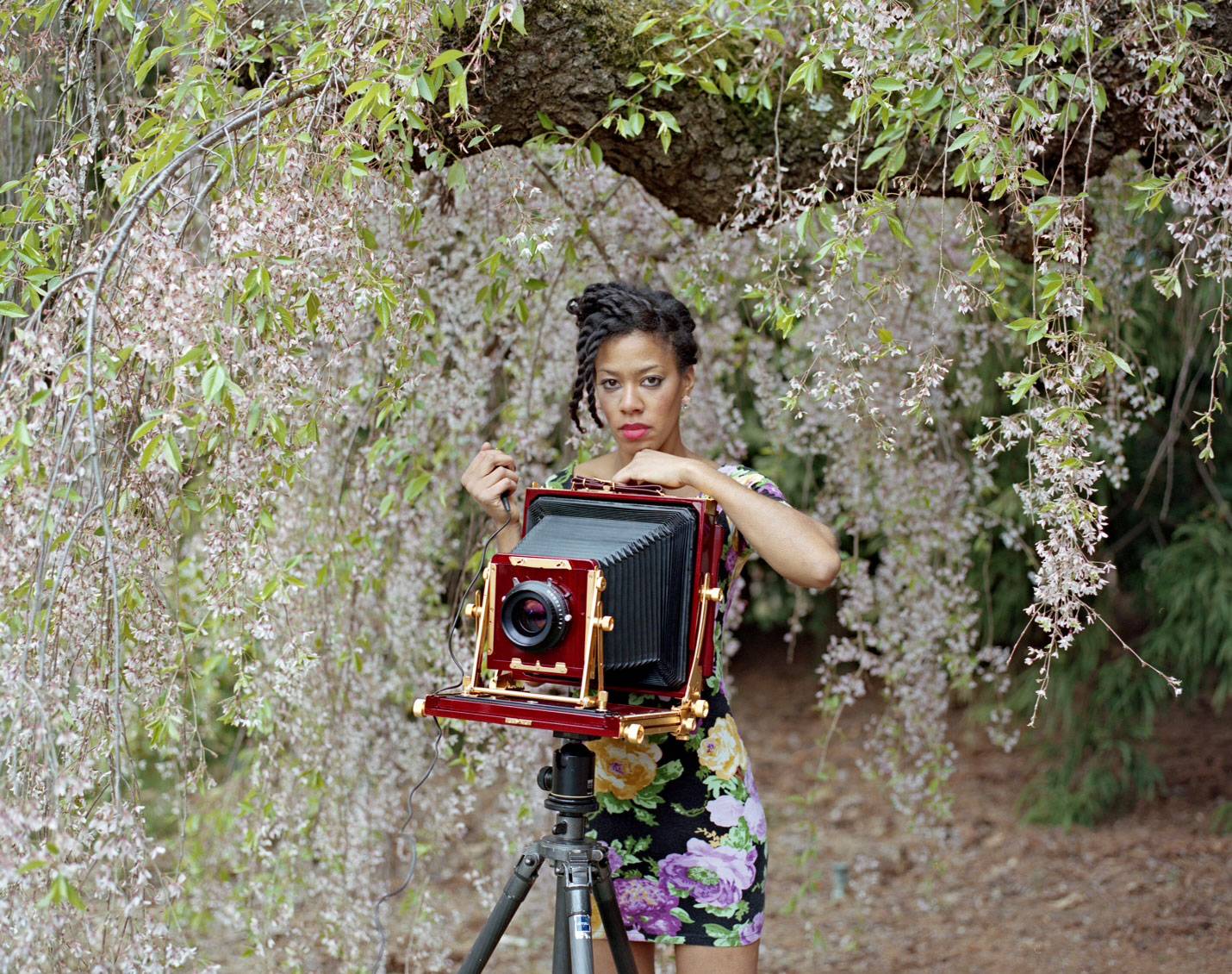 Deana Lawson behind a square-format camera amongst cherry blossoms