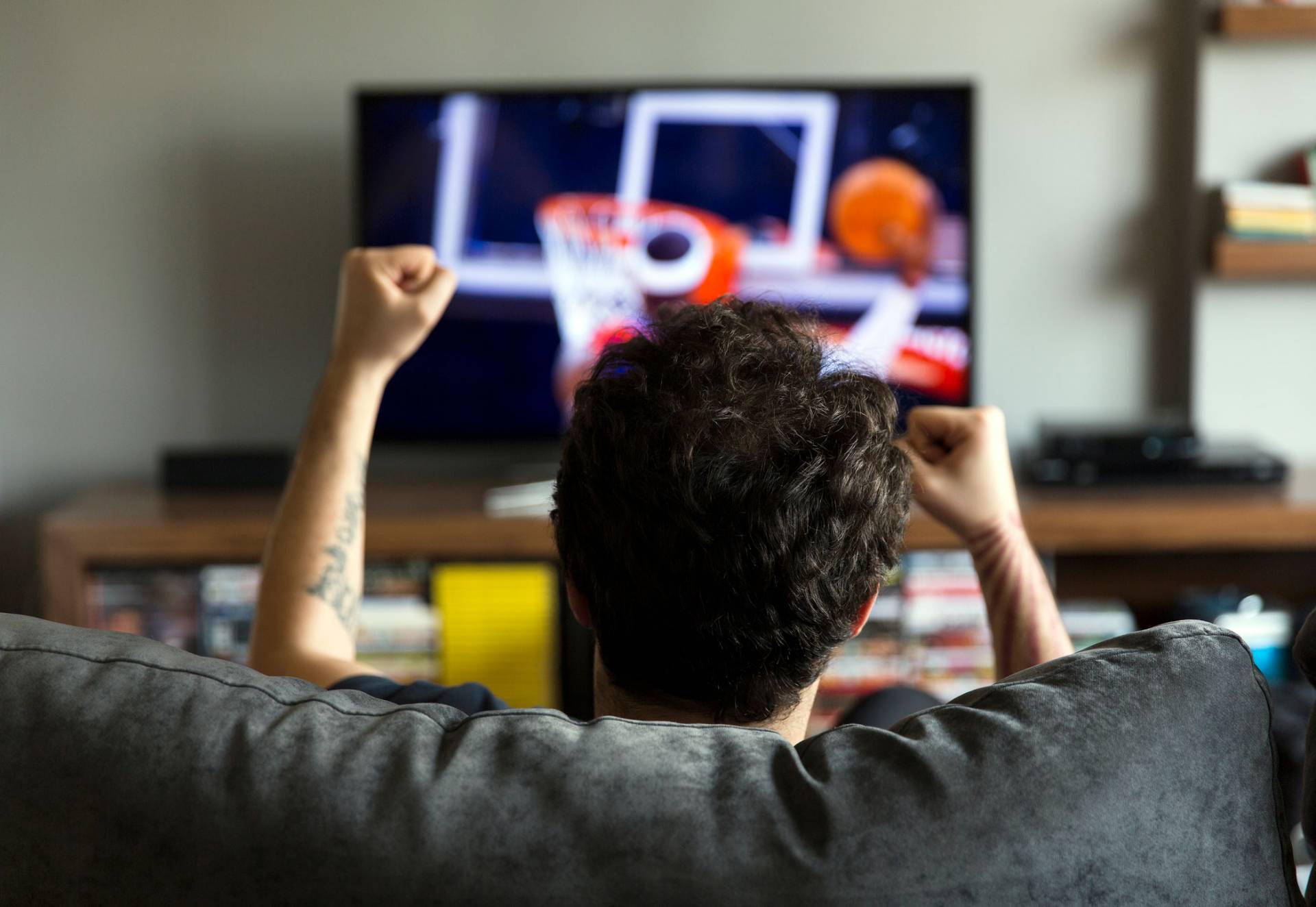 man watching basketball game on TV
