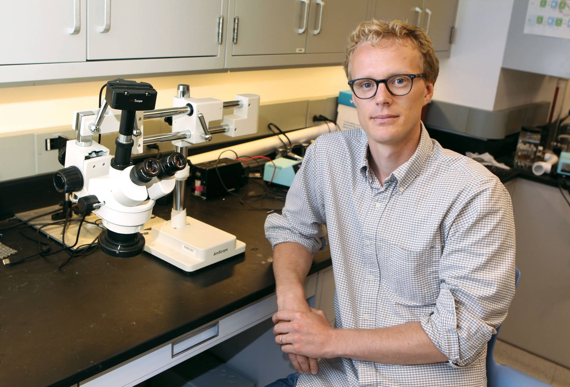 Marcus Hultmark sits next to a microscope in a laboratory