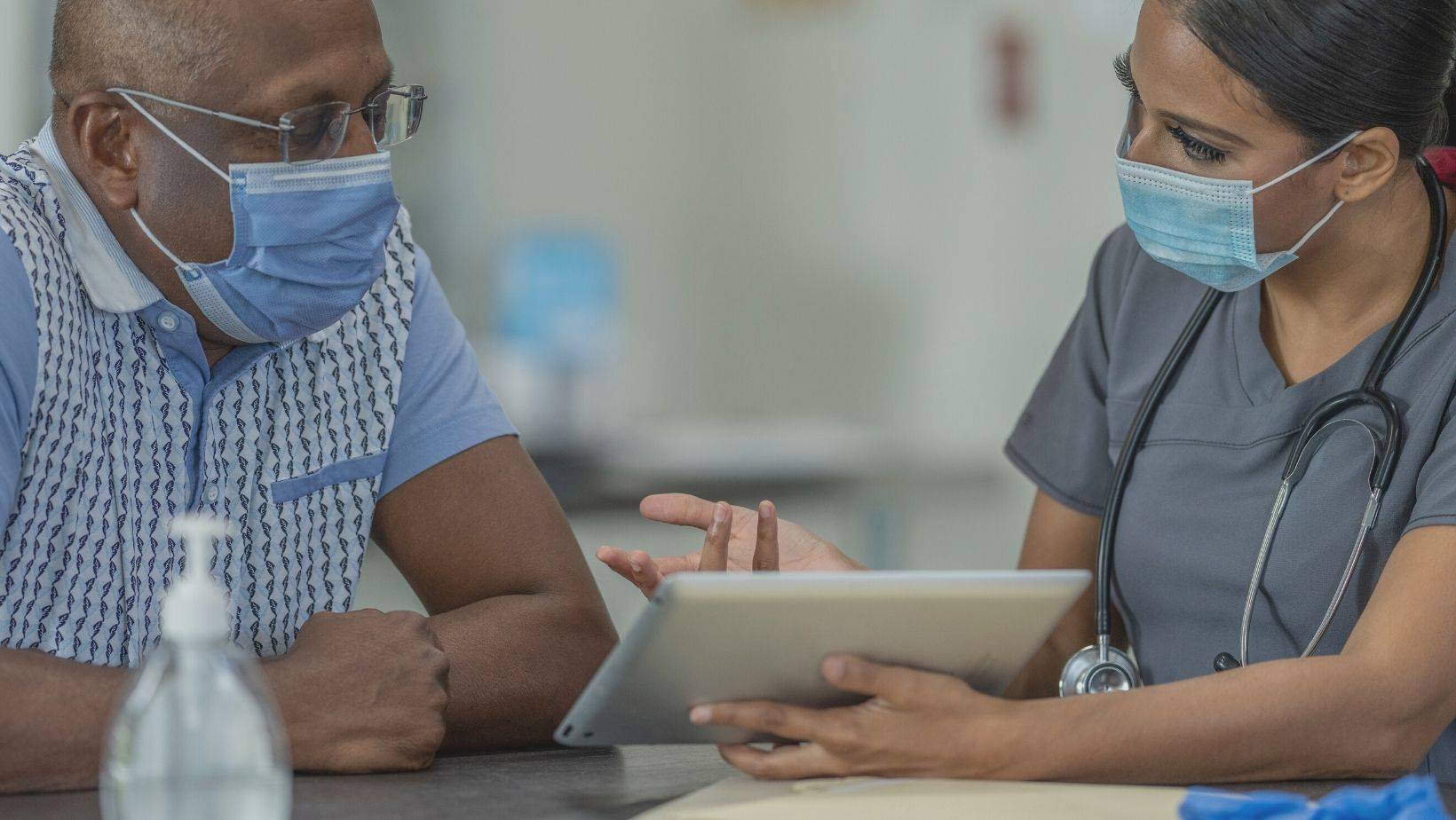 A nurse shows a man information on a tablet