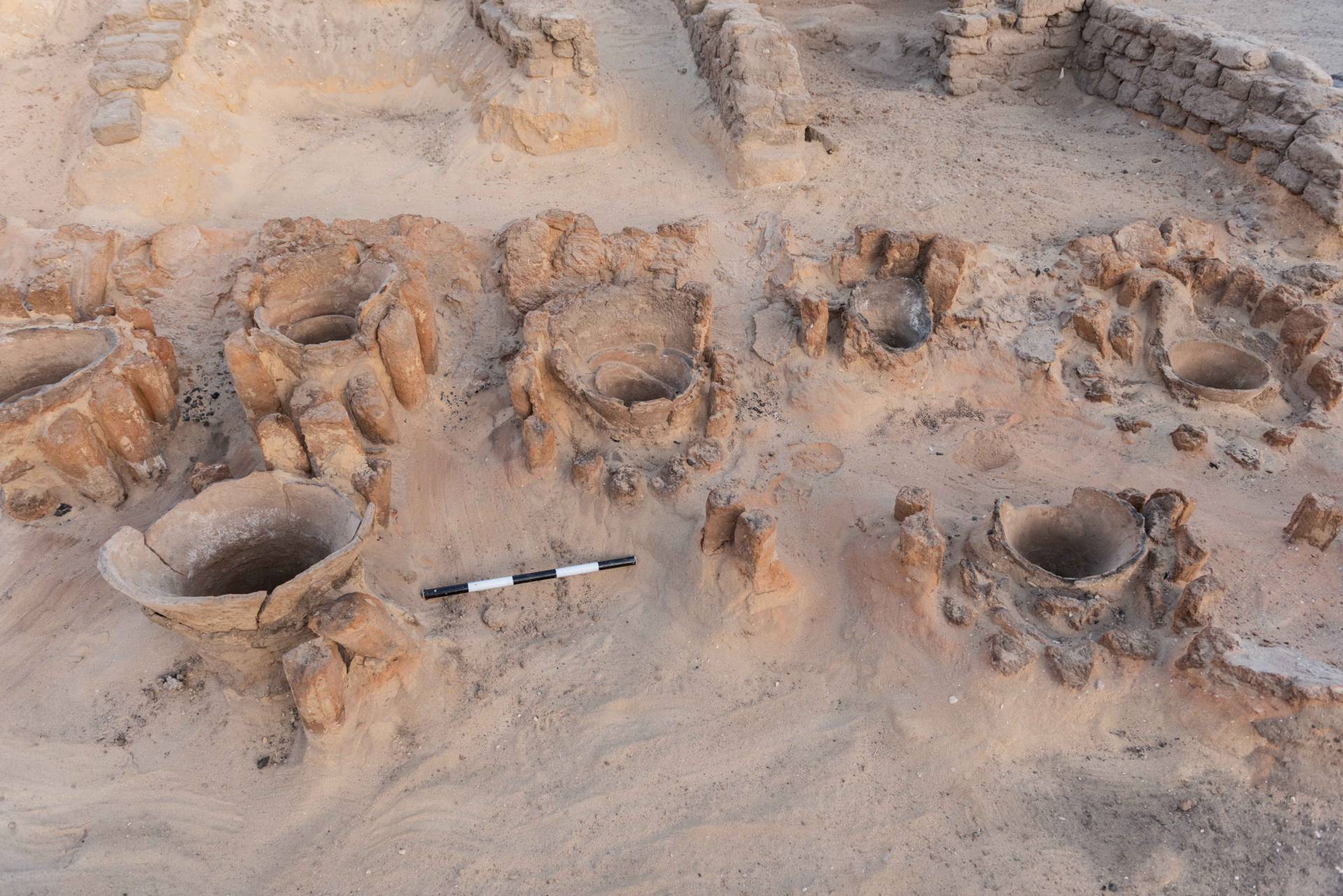Openings of urns used to hold ingredients for brewing visible in the sand