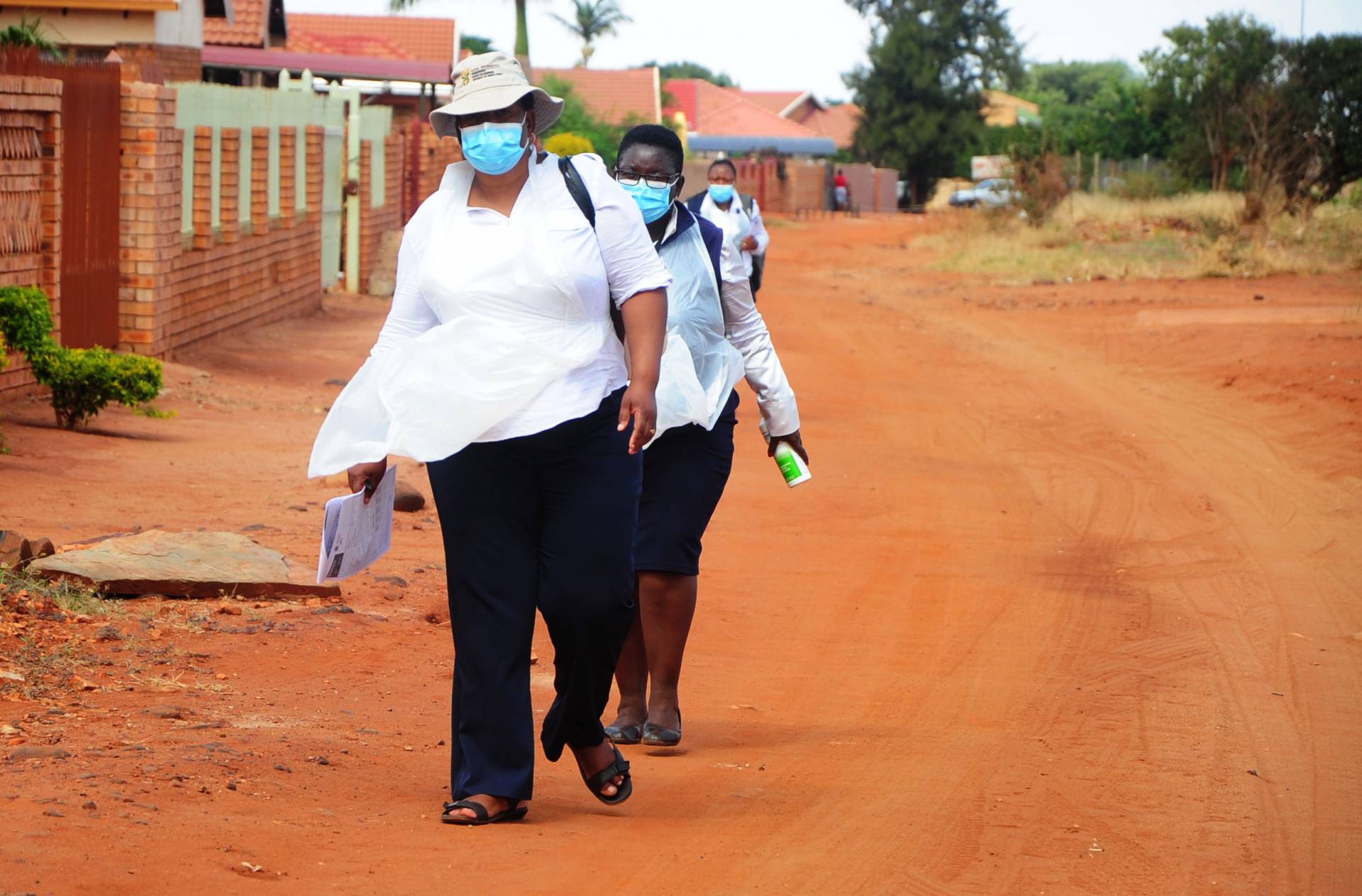 Women in masks walk along a road in Africa