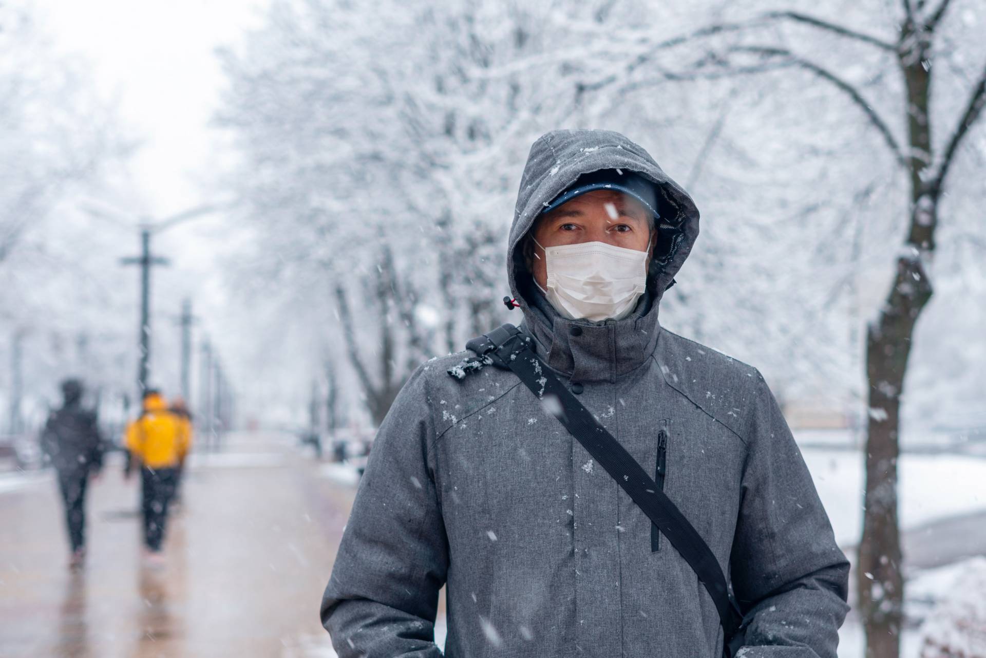 A masked person stands on a snowy walking path