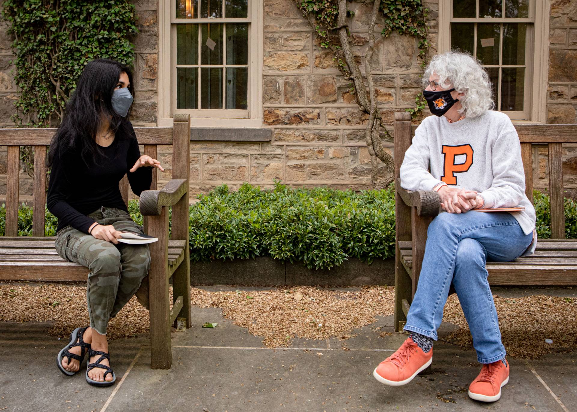 Student and Jill Dolan chat while sitting on benches