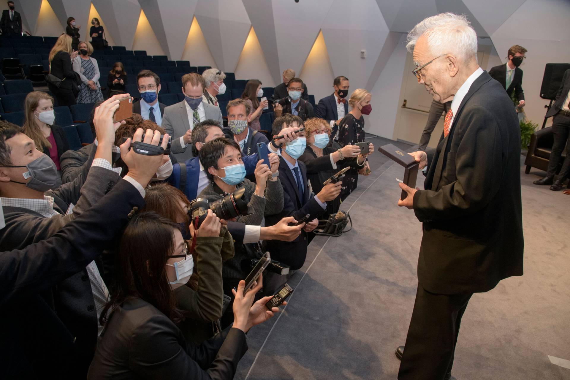 Manabe shows his Nobel medal to a throng of journalists