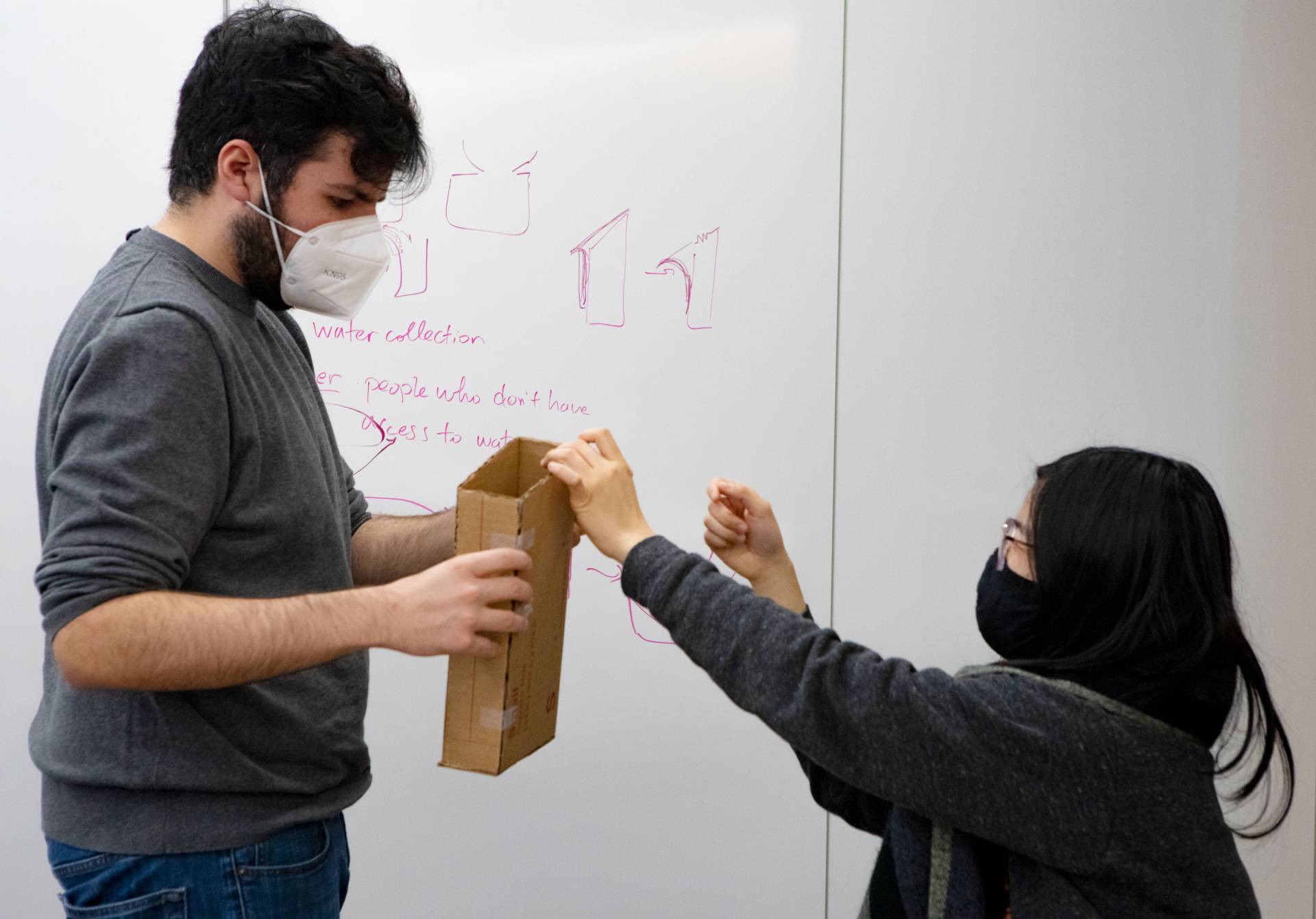 A male student holds a box for a female student
