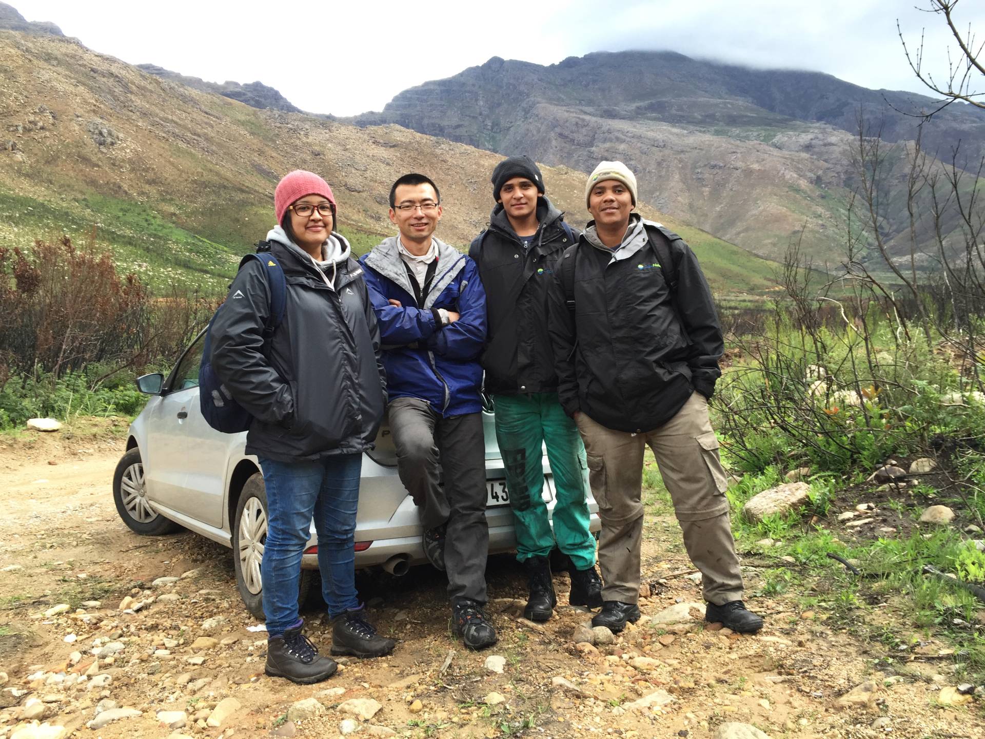 4 researchers pose with a car