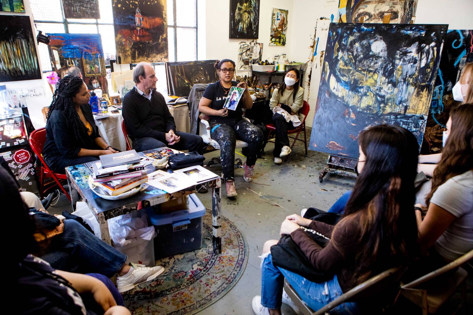 A painter presents her work surrounded by students and professors
