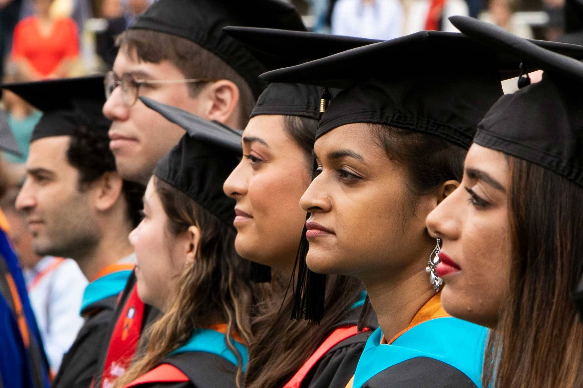profile view of graduating students as they listen to speeches