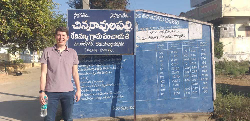 Amichai Feit standing next to a sign in India