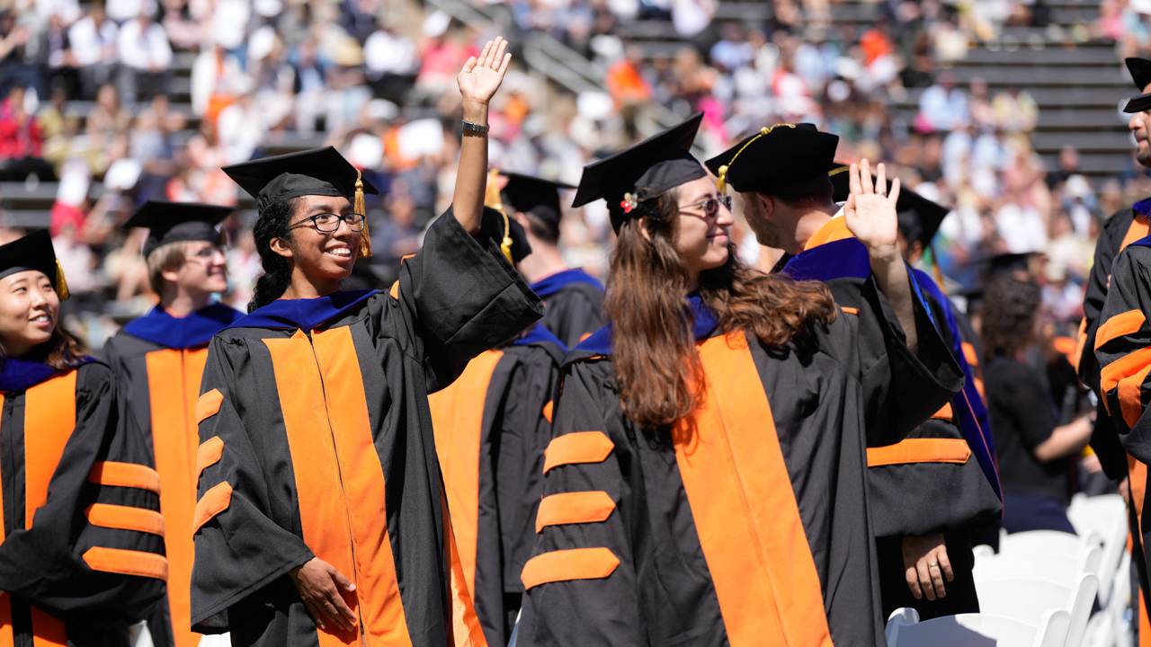 Students waving to the crowd at Commencement 