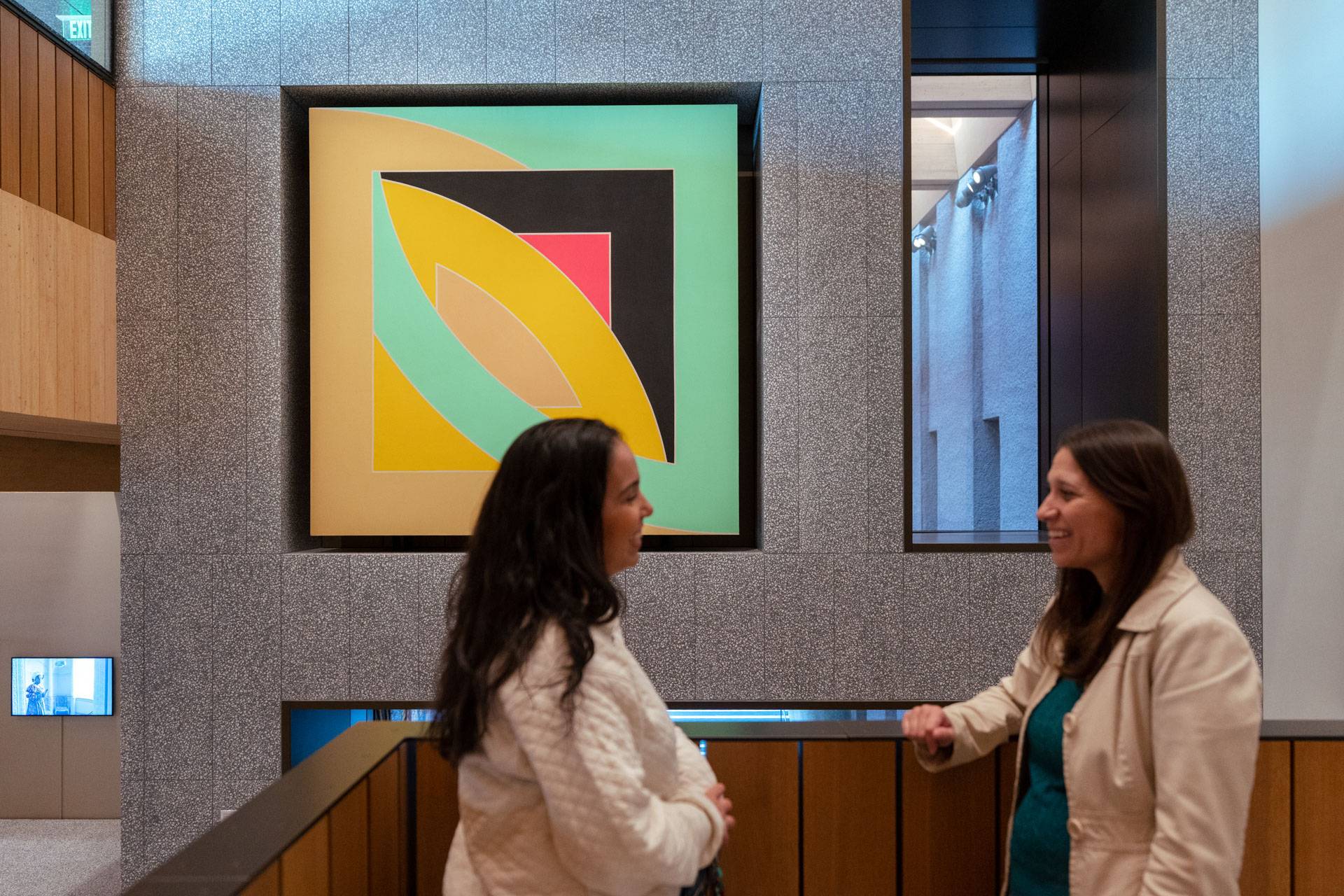 Two people talk in front of large colorful painting