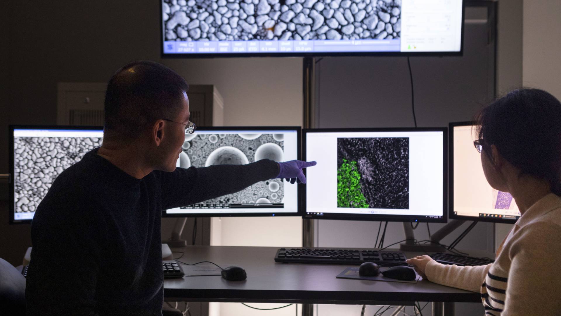 Cancer researcher Yibin Kang at a bank of monitors displaying images of biological samples