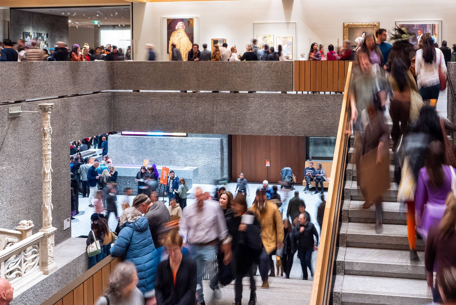 Crowds of visitors walk through an art museum 