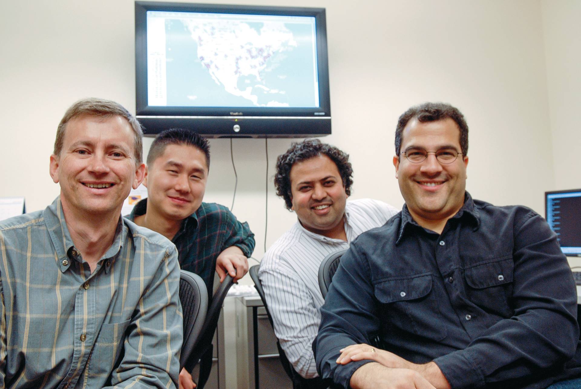 The founders of the CoBlitz content delivery network seated together beneath a map.