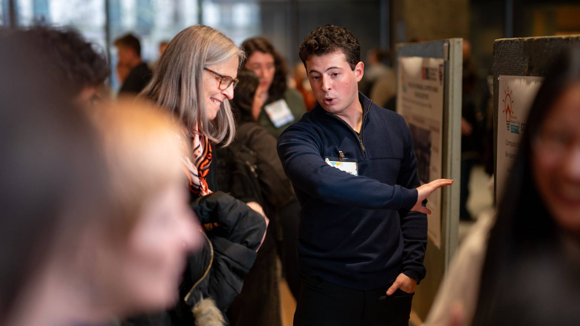Student explains poster on his work to an audience member