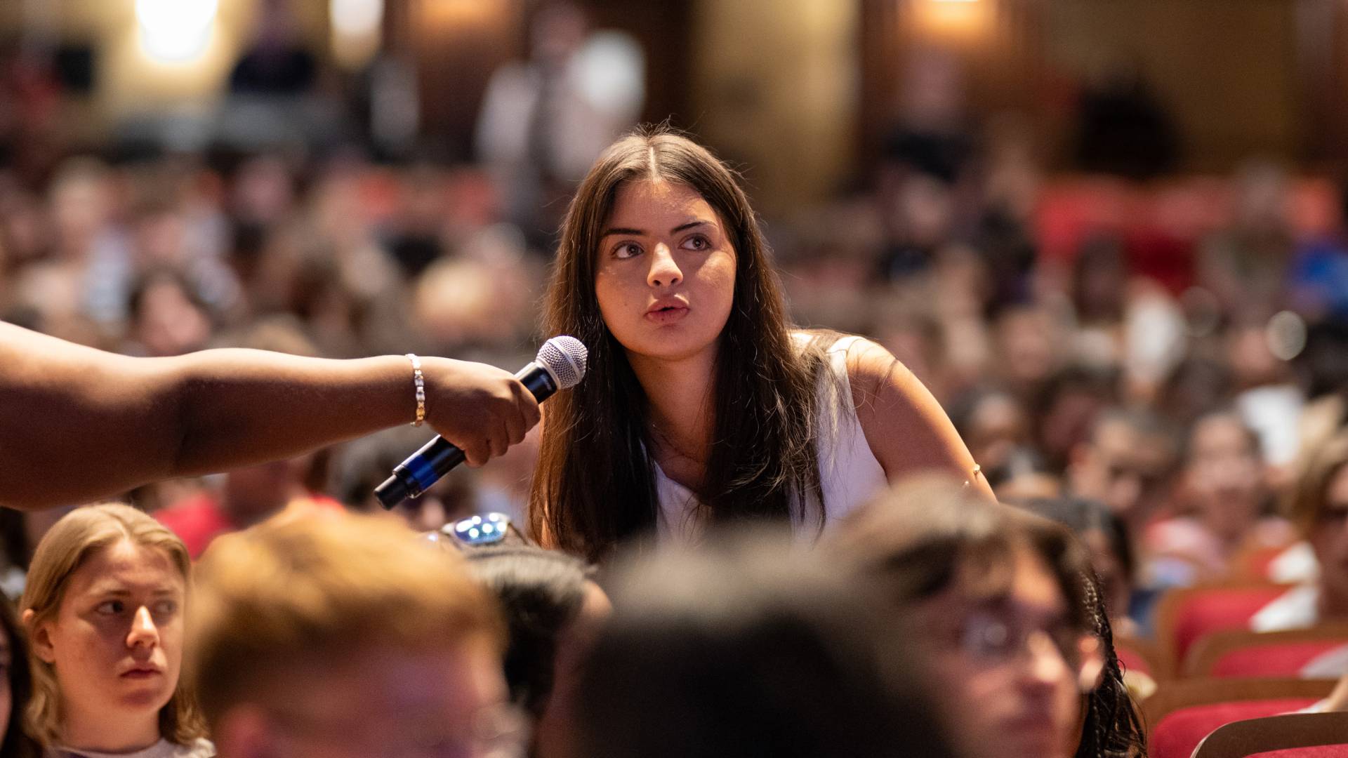 Arleen Cardenas, a student, stands in the audience to ask a question