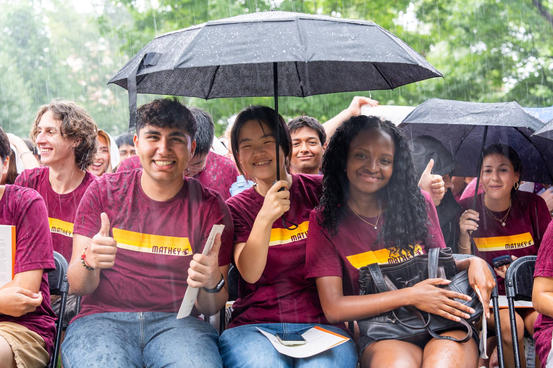 Students gather under an umbrella