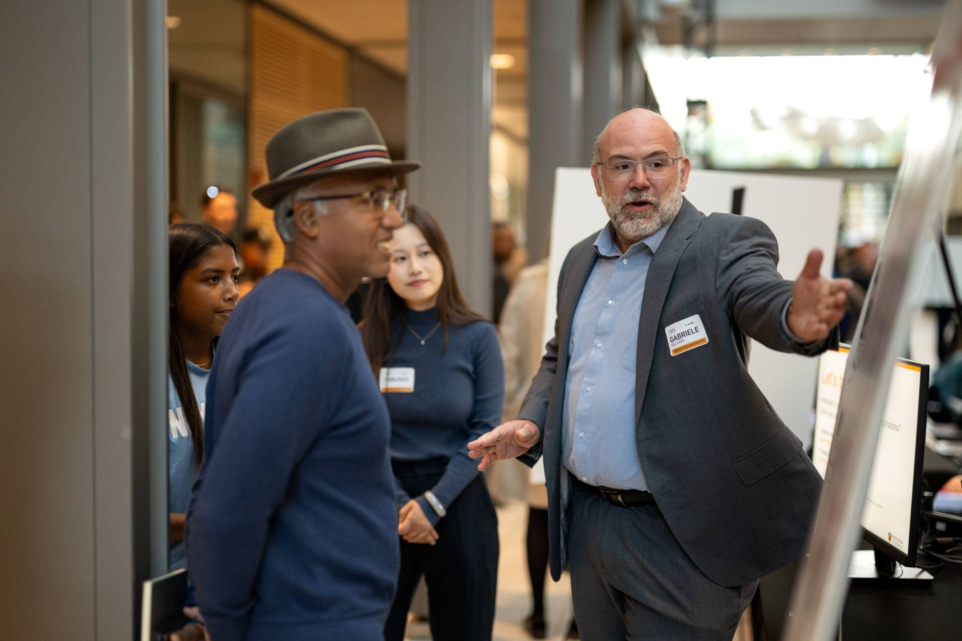 Professor Gabriele Villarini points to his poster board while presenting his research to a group of attendees