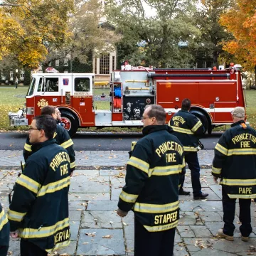 firefighters stand in front of firetruck.