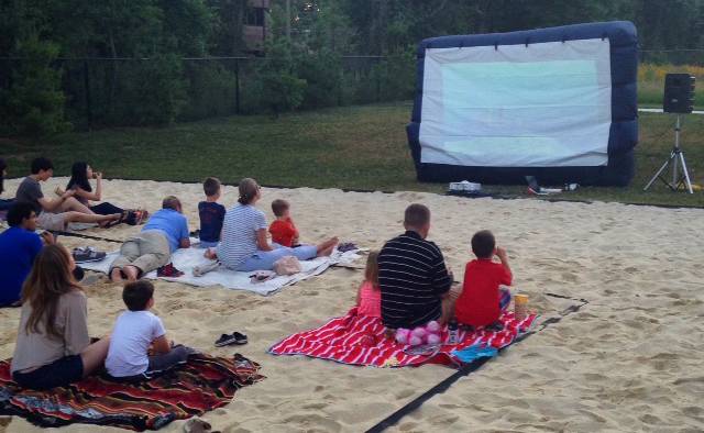 Graduate students with families watching a movie outdoors