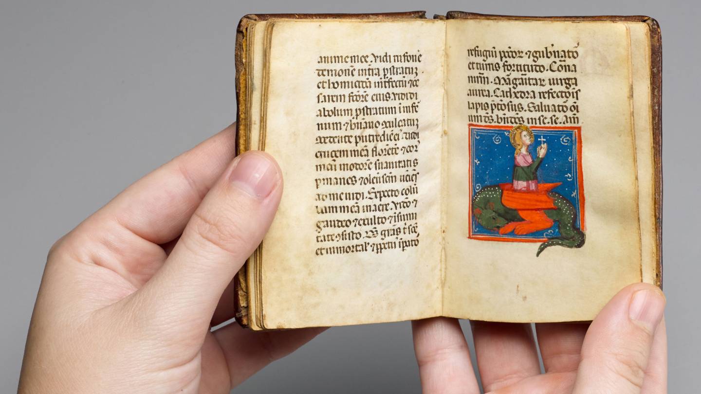 Hands holding miniature ancient illuminated manuscript